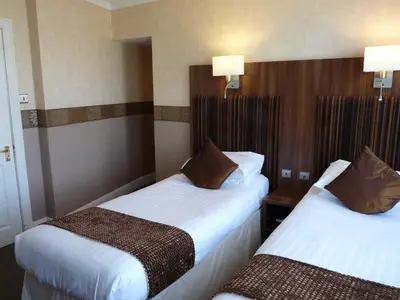 two beds in a hotel room with white sheets at The Park Hotel in Dunoon
