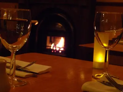 two wine glasses sitting on a table with a fireplace at The Park Hotel in Dunoon