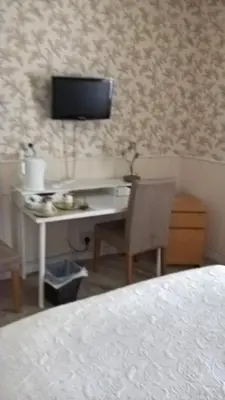 a bedroom with a desk with a television on the wall at Nethermains House in Kilwinning