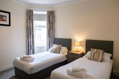 two beds in a small room with a window at Corran House Guest House in Oban