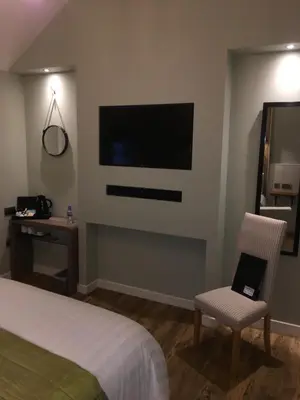 a bedroom with a bed and a tv and a chair at Rosemount Boutique B&B in Lanark