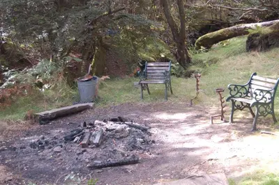 two benches sitting next to a fire in a yard at Waterfall Lodge - private waterfall and sauna in Killin