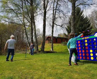 a group of people playing with a large board at Luxury woodland Alder Lodge in Killin