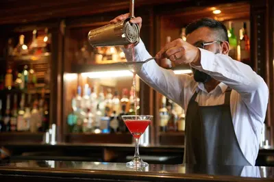 a man bartender making a drink at a bar at Dalmahoy Hotel & Country Club in Edinburgh