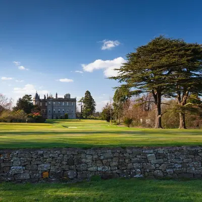 a castle on a golf course with a stone wall at Dalmahoy Hotel & Country Club in Edinburgh