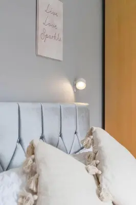 a bed with white pillows and a sign on the wall at Crewe Apartment - Stylish 2 bedroom apt, Garden, Free parking, Edin City in Edinburgh