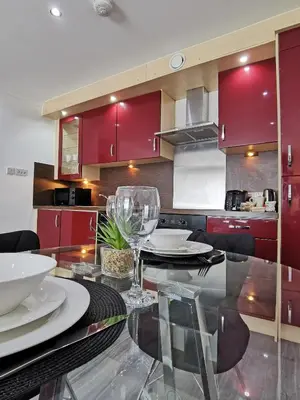 a kitchen with red cabinets and a glass table with chairs at Vkm Apartments in Glasgow