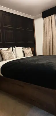 a bedroom with a large bed with a black headboard at Vkm Apartments in Glasgow