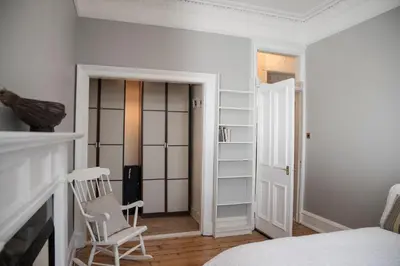 a bedroom with a bed and a chair and a fireplace at Edinburgh, Stockbridge Apartment in Edinburgh