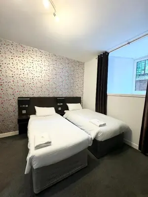 two twin beds in a room with a window at Murrayfield Park Guest House in Edinburgh