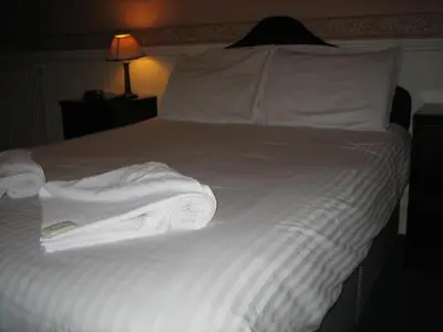 a bed with white sheets and towels on it at Murrayfield Park Guest House in Edinburgh