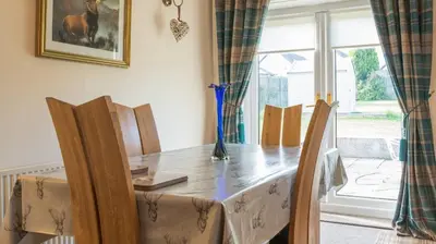 a dining room table and chairs with a vase on it at Pippin, Tranquil Scottish Cottage with Hot Tub in Airdrie