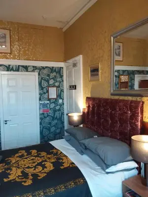 a bedroom with a bed with a mirror on the wall at IVY- Braveheart Guest House in Edinburgh
