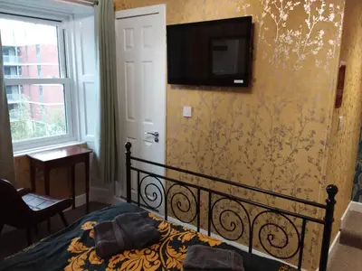 a bedroom with a bed with a television on the wall at IVY- Braveheart Guest House in Edinburgh