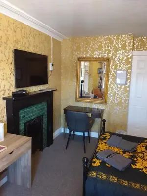 a bedroom with a bed and a desk and a television at IVY- Braveheart Guest House in Edinburgh