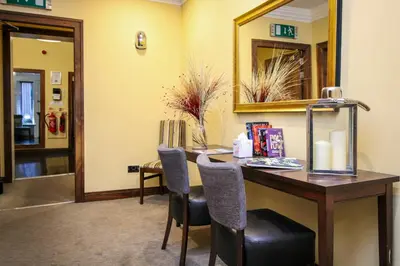 a room with a desk with chairs and a mirror at Acorn Hotel in Glasgow