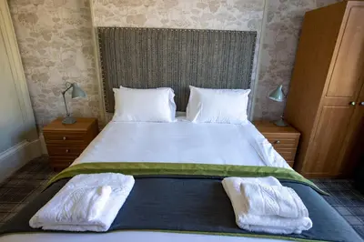 a bedroom with a large bed with two towels on it at The Waverley Hotel in Callander
