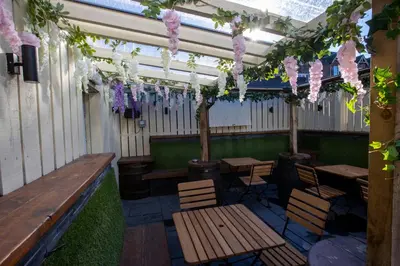 a patio with wooden tables and chairs and flowers at The Waverley Hotel in Callander