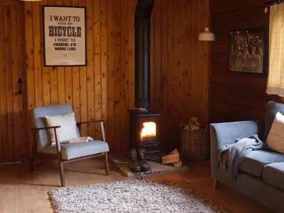 a living room with two chairs and a wood stove at Hillside Log cabin, Ardoch Lodge, Strathyre in Strathyre