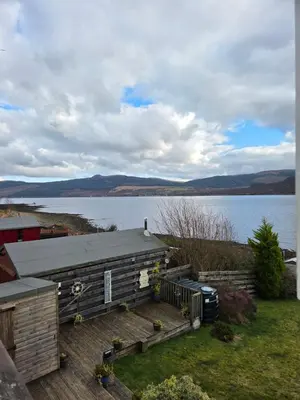 a house on a deck with a lake in the background at Tigh Na Mara in Furnace