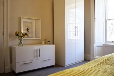 a bedroom with a white cabinet with a vase of flowers on it at Wallace View Apartment in Stirling