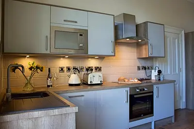 a kitchen with white cabinets and a counter top at Wallace View Apartment in Stirling