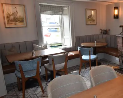 a restaurant with tables and chairs and a window at Elphinstone Hotel in Biggar
