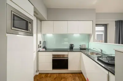 a kitchen with white cabinets and a sink and a microwave at Destiny Scotland -The Malt House Apartments in Edinburgh