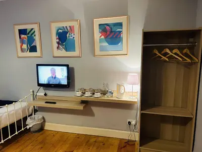 a living room with a television on a table with a shelf at Ardenlee Guest House in Edinburgh