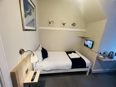 a small room with a bed and a desk with a lamp at Ardenlee Guest House in Edinburgh