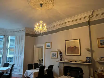 a dining room with a chandelier and a fireplace at Ardenlee Guest House in Edinburgh