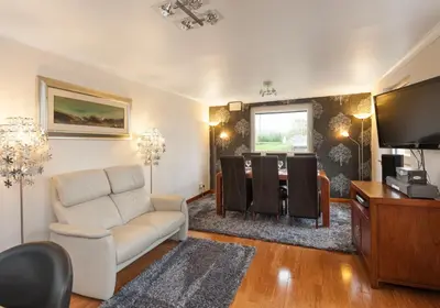 a living room with a white couch and a television at The Traquair Park Residence in Edinburgh