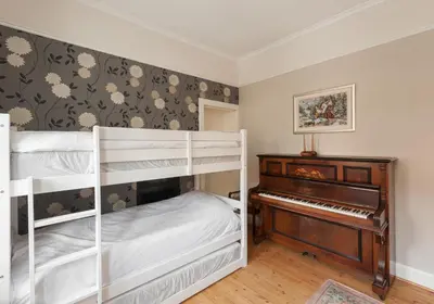 a bedroom with two bunk beds and a piano at The Traquair Park Residence in Edinburgh