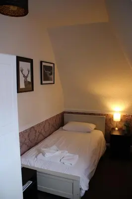 a bedroom with a bed in a room with a lamp at Ardmillan Hotel in Edinburgh