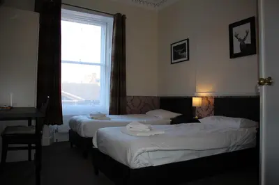 two beds in a hotel room with a window at Ardmillan Hotel in Edinburgh
