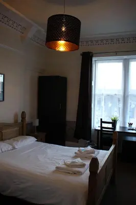 a bedroom with a bed with white sheets and a window at Ardmillan Hotel in Edinburgh