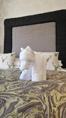 a white stuffed animal sitting on top of a bed at The Abbotsford in Callander