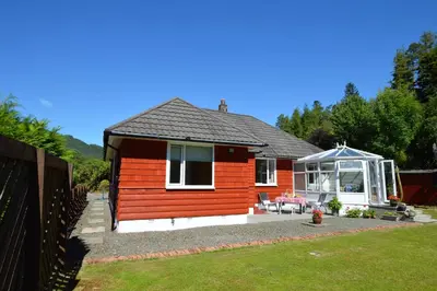 a small red house with a gazebo at Cedar Cottage in Dunoon