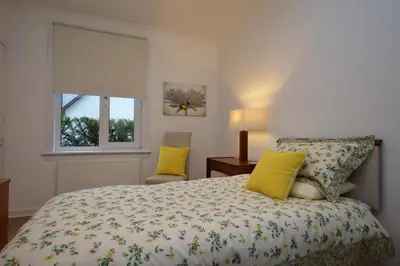 a bedroom with a bed with yellow pillows at Cedar Cottage in Dunoon
