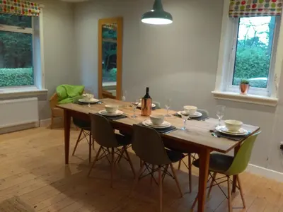 a dining room table with chairs and a bottle of wine at Lowood Cottage in Edinburgh