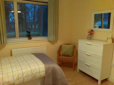 a bedroom with a bed and a dresser and a window at Lowood Cottage in Edinburgh
