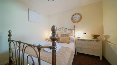 a bedroom with a bed and a clock on the wall at The Old Tramhouse Self Catering Apartments in Stirling