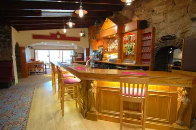 a bar in a restaurant with wooden bar stools at The Galley Of Lorne Inn in Ardfern