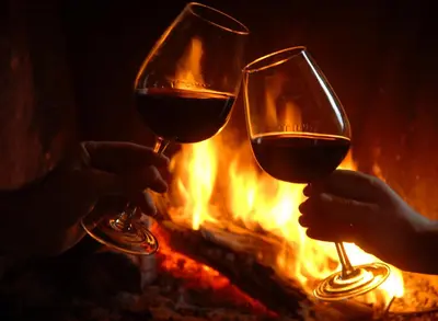 two people holding wine glasses in front of a fire at The Galley Of Lorne Inn in Ardfern