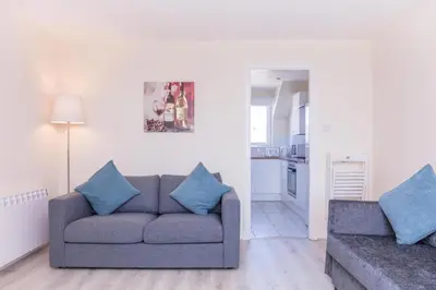 a living room with a gray couch and blue pillows at Ailsa Retreat in Troon
