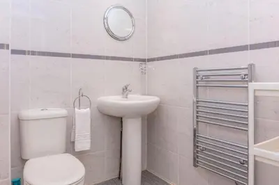 a white bathroom with a toilet and a sink at Ailsa Retreat in Troon