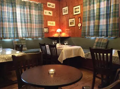 a dining room with a table and chairs and curtains at Ashbank Hotel in Carradale