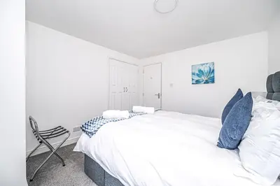 a white bedroom with a bed and a chair at Super Prime Luxury Waterfront View DBay by TBA in Saint Davids