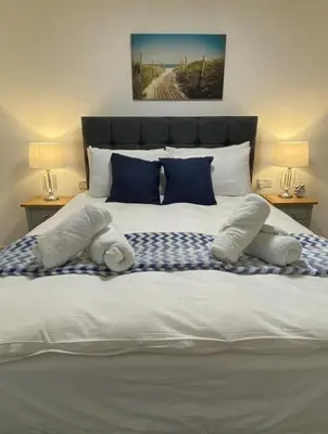 a large bed with blue and white pillows on it at Super Prime Luxury Waterfront View DBay by TBA in Saint Davids