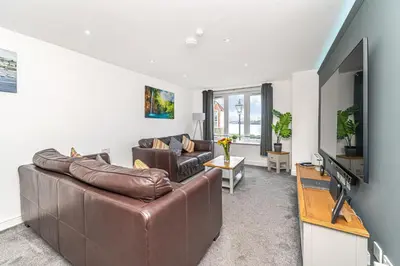 a living room with a leather couch and a flat screen tv at Super Prime Luxury Waterfront View DBay by TBA in Saint Davids